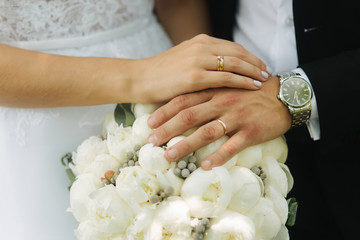 Obraz na płótnie Canvas Groom and bride put their hands on the bouquet