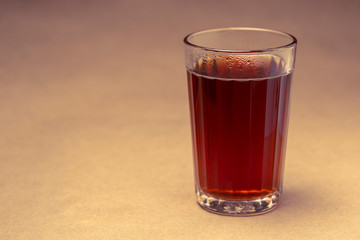 Glass with black tea on a brown background