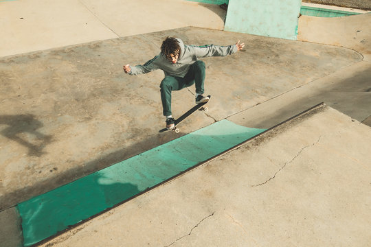Guy practicing skateboarding and doing tricks in a ska.tepark. Skateboarder jumping