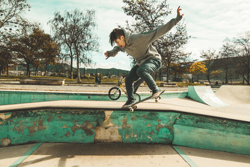 Guy practicing skateboarding and doing tricks in a skatepark. Skateboarder jumping