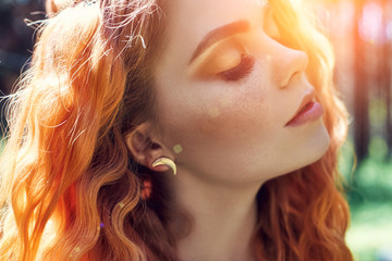 Beautiful redhead Norwegian girl with big eyes and freckles on face in the forest. Portrait of...