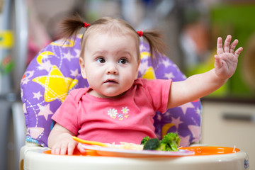 pretty baby toddler girl eating vegetable at home kitchen