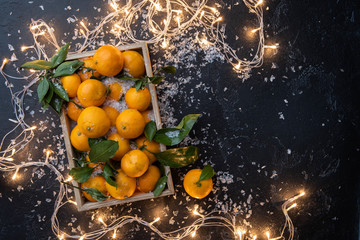 Fototapeta na wymiar Photo of tangerines in wooden box on black table