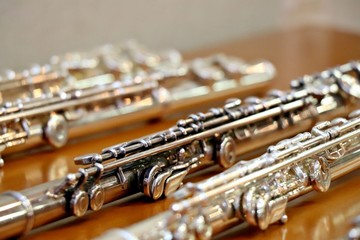 Blurry soft focused set of silver flutes on the wooden table close up. Musik background. Selected focus.