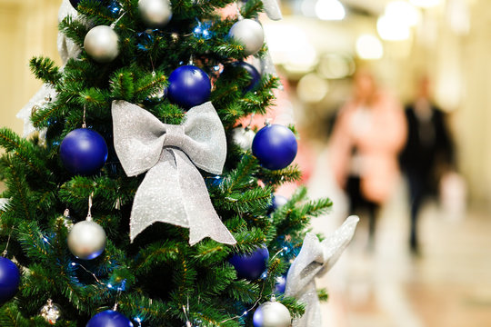 Image of decorated Christmas spruce with white and blue balls in store .