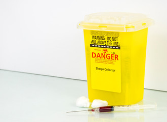 Sharps collector for used needles. Says DANGER, and Sharps Collector. Universal biohazard symbol on...