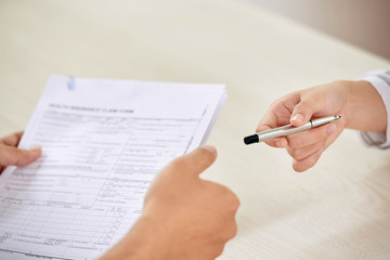Crop person giving pen to colleague for signing paper contract on business meeting