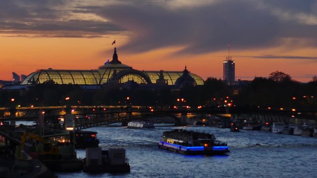 View on the Grand Palais (old monument in Paris). In the foreground there is the seine river and a boat. Filmed in the night.
