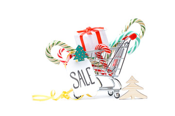 Photo of iron cart with box with gift, caramel canes, cards on white background