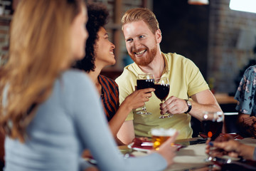 Friends making a toast while sitting in restaurant. Multi-ethnic group.