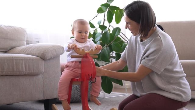 Mother with baby girl on rocking deer toy