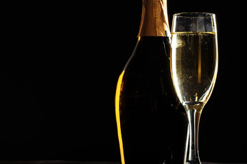bottle of champagne and glasses over dark background