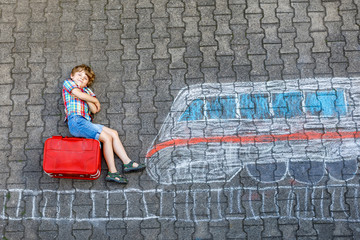 Little kid boy having fun with fast train picture drawing with colorful chalks on asphalt. Child...