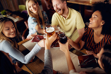 Friends making a toast while sitting in restaurant. Multi-ethnic group.