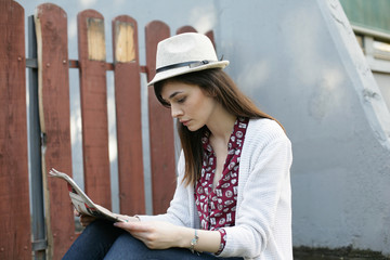 Young woman is reading newspaper outdoor.