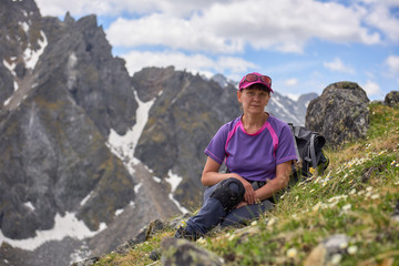 Tourist sitting resting on sloping mountain glade