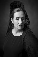 Spanish woman wearing the traditional black veil (mantilla) and high comb (peineta).