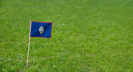 Guam flag. Photo of Guam flag on a green grass lawn background. Close up of national flag waving outdoors.