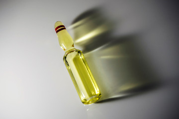 Vial detail with yellow medication, isolated side shadow on white background