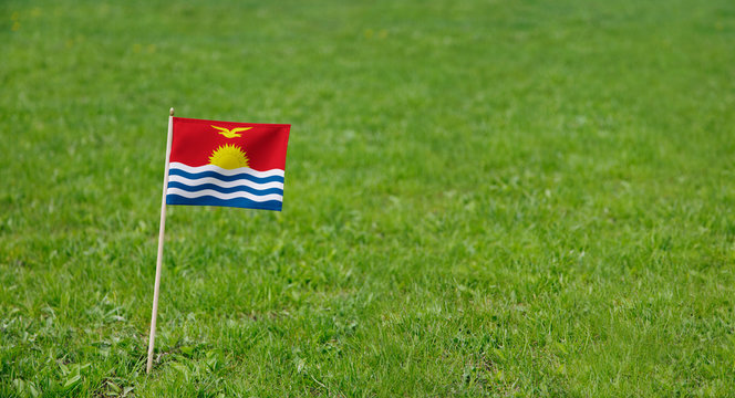Kiribati flag. Photo of Kiribati flag on a green grass lawn background. Close up of national flag waving outdoors.