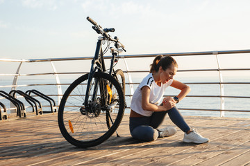Beautiful young fitness girl outdoors with a bicycle