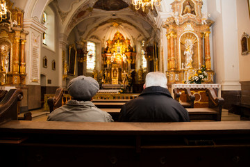 Elderly couple, man and woman pray together in church