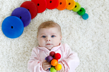 Cute adorable newborn baby playing with colorful wooden rattle toy ball on white background. New...