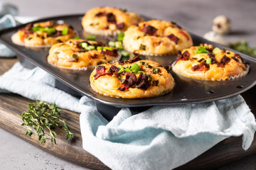 Savory muffins with bacon, quail egg, green onion cheese on a grey stone backdrop. Protein breakfast. Rustic style.