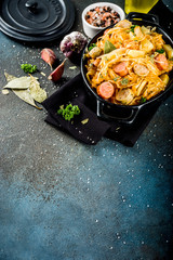 German, polish, Austrian cuisine dish, Bigos - sauerkraut cabbage stewed with meat, mushrooms and sausages, in small pan on dark concrete background.Top view with copy space.