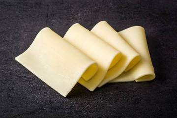 Yellow cheese slices on black slate
