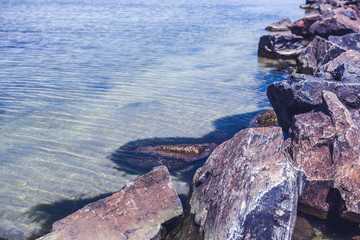 Rocky seaside with ripple waves on transparent sea water surface in sunny morning.Beauty of nature for wallpaper design