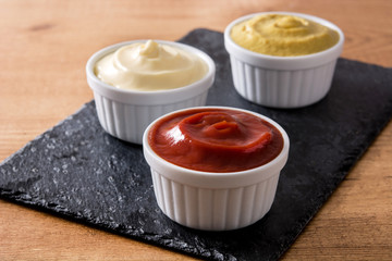 Ketchup,mustard and mayonnaise in a bowls on black slate