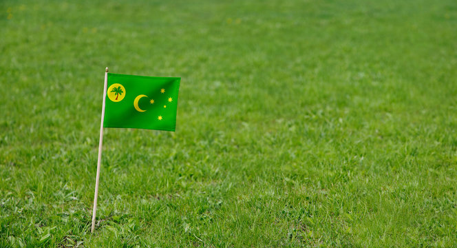 Cocos Keeling Islands flag. Photo of Cocos Keeling Islands flag on a green grass lawn background. Close up of national flag waving outdoors.