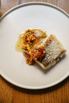 Hake fish served with vegetables on a white plate
