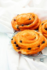 Homemade sweet buns with cinnamon and raisins on a light background.