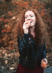 Smiling red-haired woman with tangerines outdoor.
