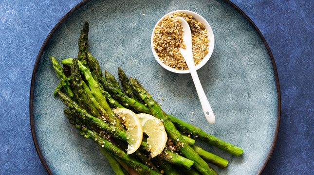 Chargrilled asparagus garnished with dukkah and lemon slices.