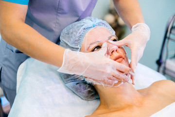 Obraz na płótnie Canvas Young pretty woman enjoying a facial mask procedure