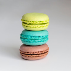 Green, turquoise and brown french macarons on the grey background. Close-up, front view, copy space