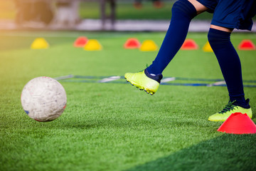 Soccer player jump and stomp for trap and control football with blurry marker cones and  ladder drills.