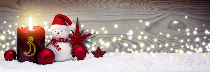 Christmas background with third Advent candle and Snowman with red decoration.