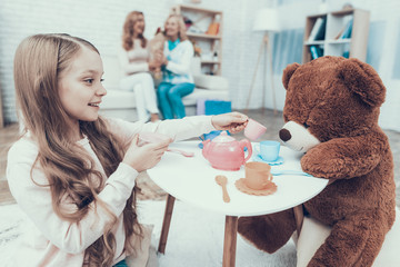 Young Girl Playing with Big Plush Bear at Home.