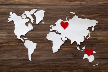 Red felt hearts and world map cutted from white paper on the wooden background. Long-distance relationships concept - Russia and Australia. Flat lay, top view, copy space, mock up