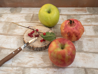 Fruit set of apples, pomegranate, a twig of wild apples on a wooden table