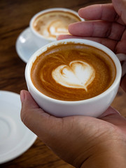 Girl holding cup of cafe latte on wooden table