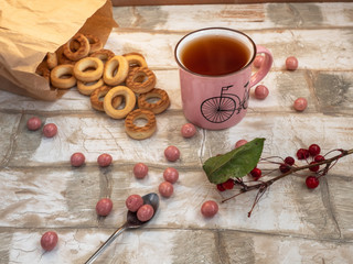 Light lunch of bagels scattered on the table, a sprig of wild apple trees, tea with a teaspoon