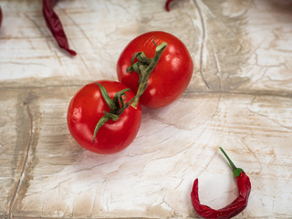 Two red pomir, hot pepper on a light wooden table