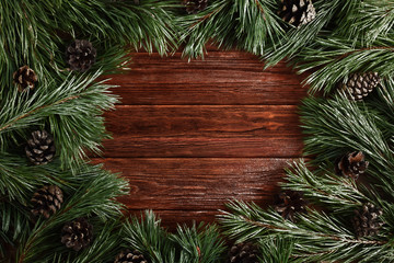 Wooden background surrounded with pine cones and branches. Christmas background with empty space