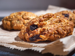 Oatmeal cookies with cereals and raisins on a paper bag, close-up.