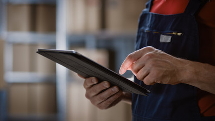 Close-up on a Man's Hands Using Digital Tablet Computer while Standing in the Warehouse.